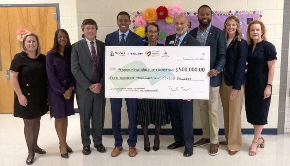Group of nine people holding a ceremonial check for $500,000 made out to the Newport News Education Foundation, dated December 10, 2024, presented by BayPort Credit Union and Ferguson